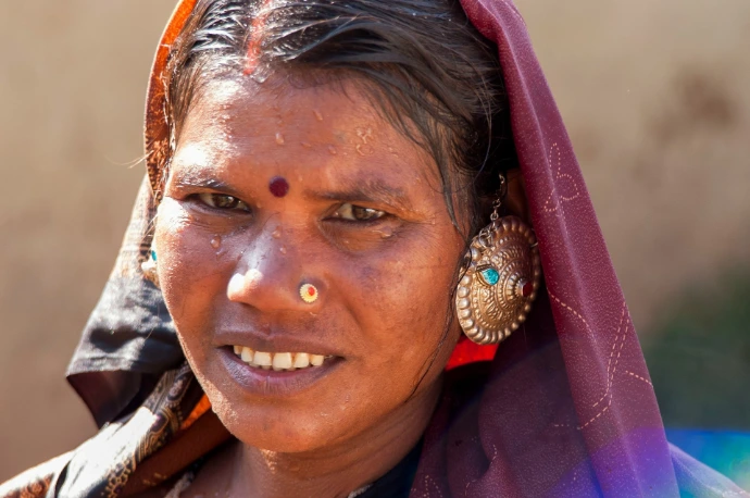 एक महिला मुस्कुराती है, आभूषण से सजी हुई।